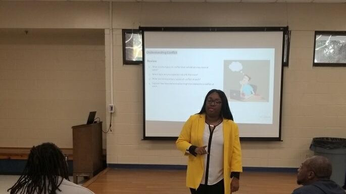 Alyssa Hogan presenting beside a projected slide headed Understanding Conflict