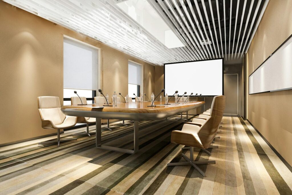 Long boardroom table set with microphones, facing a projection screen