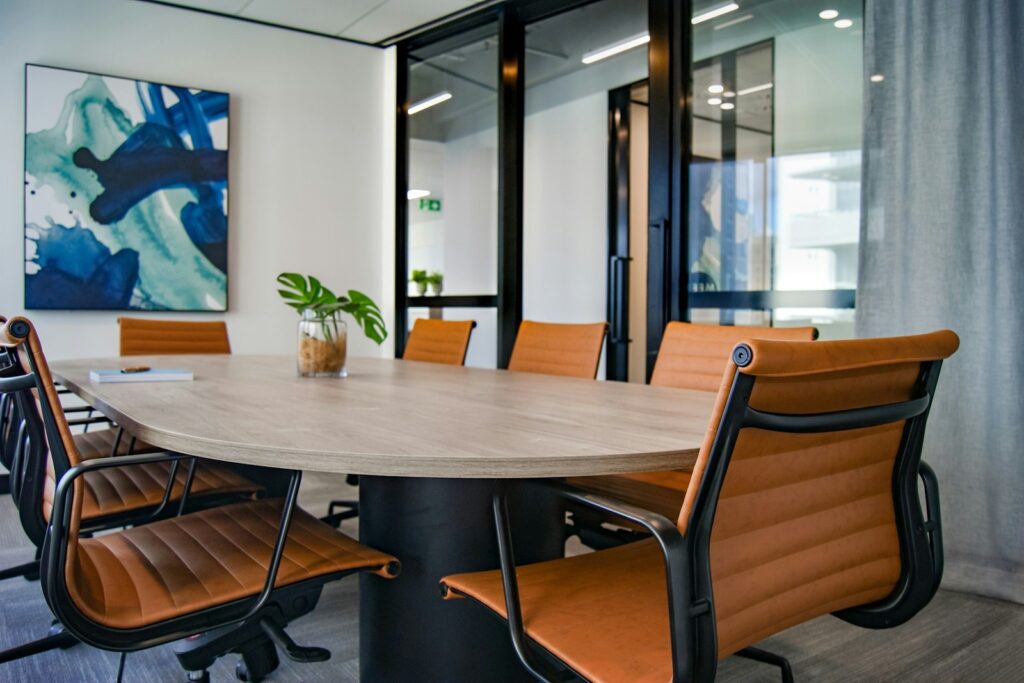 Boardroom with an oval table and tan leather chairs beside a glazed wall