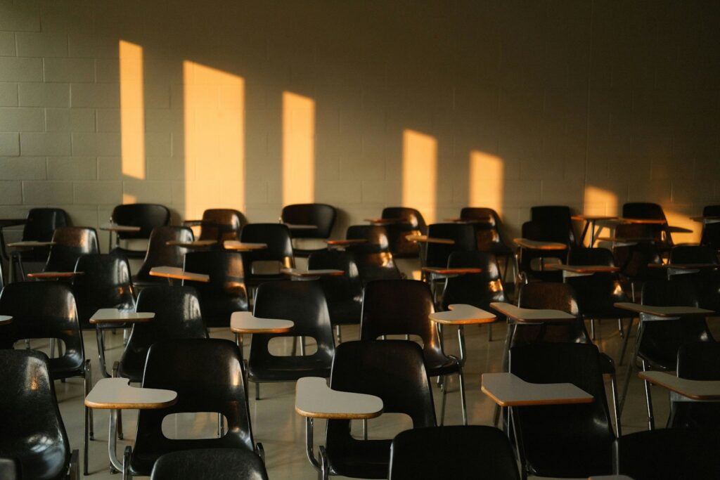 Empty classroom with tablet arm chairs and afternoon light across the wall