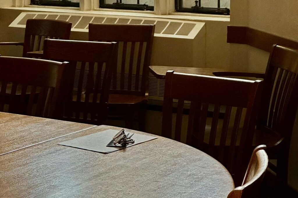 A round table and wooden chairs in a panelled meeting room