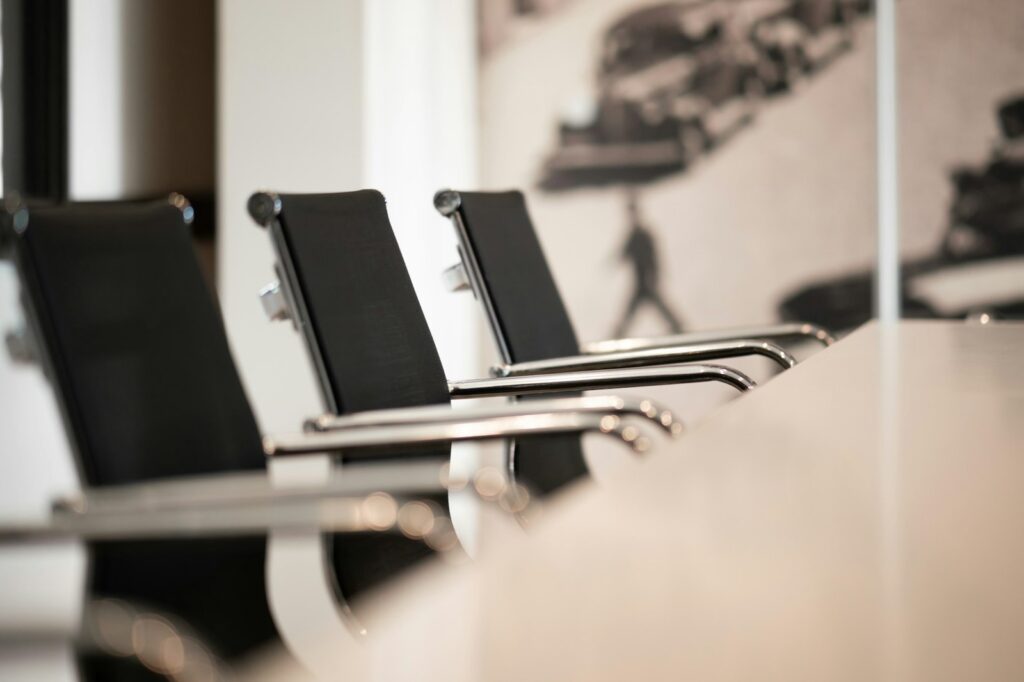 A row of black office chairs along a white conference table