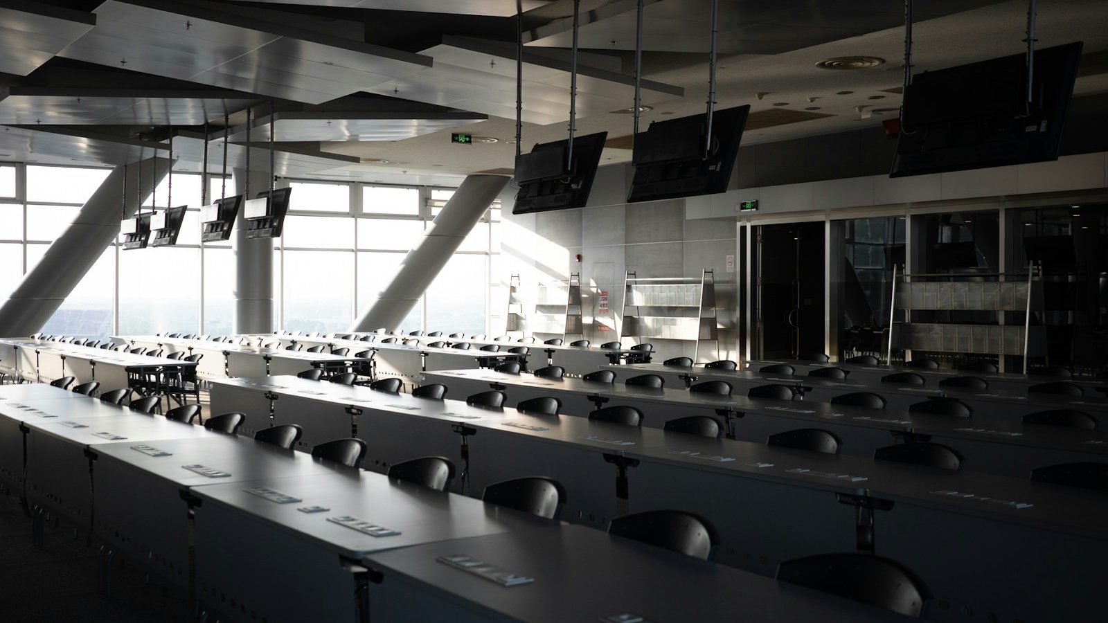 Tiered lecture room seen from the back, rows of desks facing the front