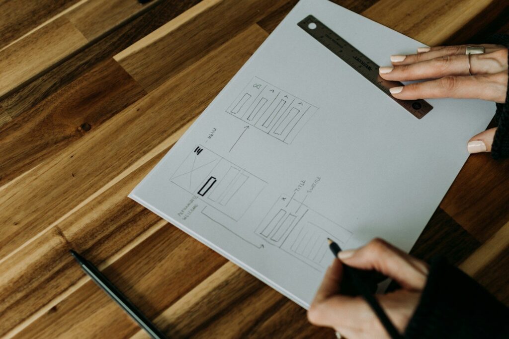 Two hands working over a printed plan on a wooden table
