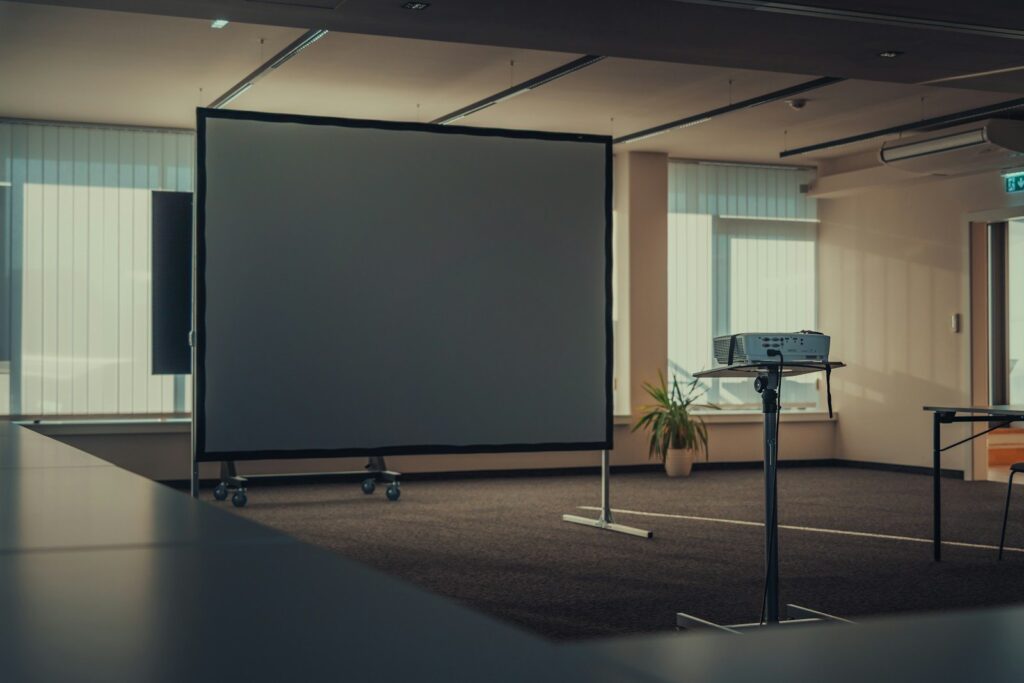 Empty meeting room with a projection screen on a rolling stand