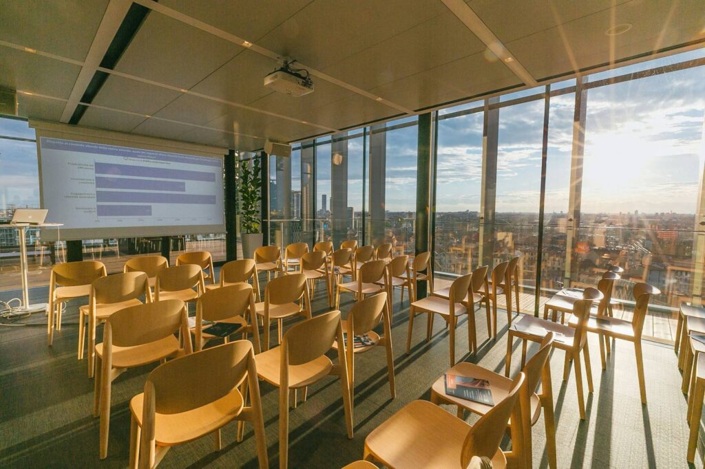 Training room with rows of wooden chairs facing a projected chart, city visible through the windows